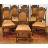 Set of six carved oak dining chairs with dolphin and urn top rails, upholstered in brown leather