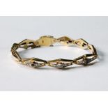 Early 20th century gold bracelet of pierced lozenge-shaped links, three set with diamonds and