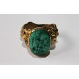 Gold signet ring carved with a seated classical figure, the shoulders modelled as naked women.