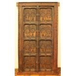 Carved hardwood door having eight fielded panels depicting figures framed by a floral border, 182cm