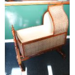 Victorian mahogany hooded cot with caned panels raised on turned H-frame stand,