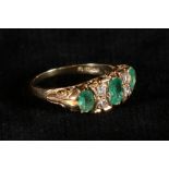 Victorian emerald and diamond ring with three oval cut emeralds and four diamond points, in scroll