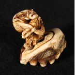 Japanese ivory carving of an oni carrying a large sack on his back, a.f. and an associated stand
