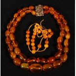 Two amber necklaces, the first of graduated oval form, largest 2cm long, 23cms long, the other