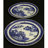 Pair of late 18th century blue and white oval dishes with armorial details, the central panels