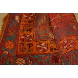 Ginger ground Turkish carpet with  stylised flower heads on central red fields and blue and yellow