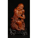 A 19th Century Chinese nicely carved wood model of Pu Tai seated on a large bag holding his knees,