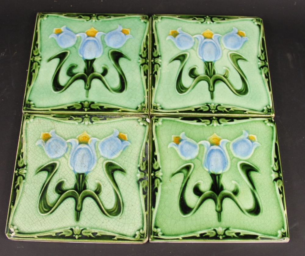 Four Art Nouveau ceramic tiles, decorated with stylised flowers,