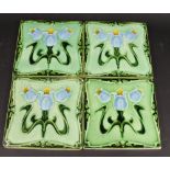 Four Art Nouveau ceramic tiles, decorated with stylised flowers,