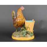 A Minton majolica hen figure by John Henk, 1880, the hen modelled standing beside a wooden box,