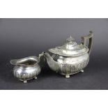 A silver tea pot and cream jug, with gadrooned decoration, ebonised handles, Walker & Hall,