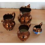 Four graduated copper lustre jugs, the smallest with floral enamelled banding, largest 16.
