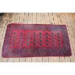 A Baluch red ground wool rug,