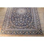 A Persian Kashan wool carpet, worked with an all over floral design against a blue ground,