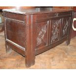 An early 18th century oak coffer, with hinged top and later carved panelled front on stile feet,