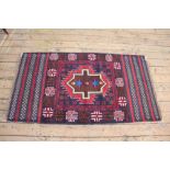 A Baluch wool rug, worked with an overall geometric design against a blue ground,