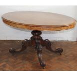 A Victorian walnut oval loo table, with quarter veneered top on carved scroll legs,