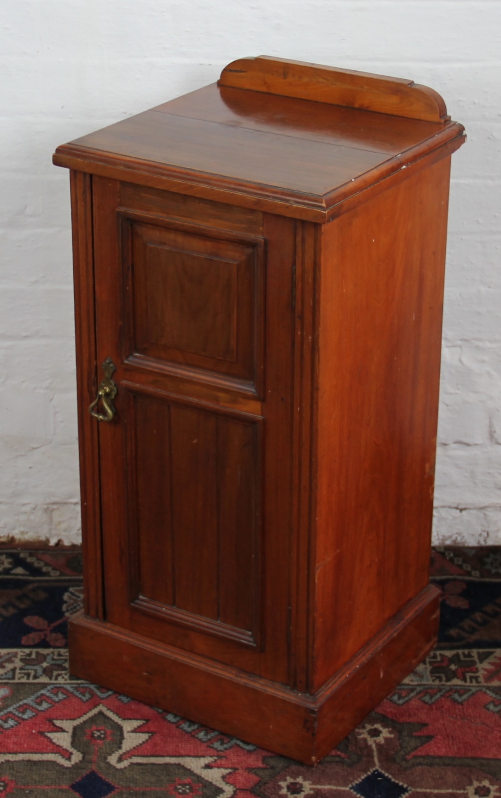 A late Victorian walnut bedside pot cupboard, on plinth base, with label verso for W. H.