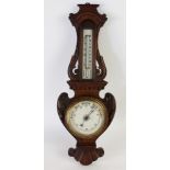 A late Victorian carved oak aneroid barometer,