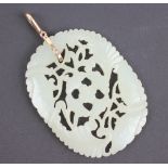 A carved jade pendant, the lozenge shaped panel carved with moths, flowers and foliage,