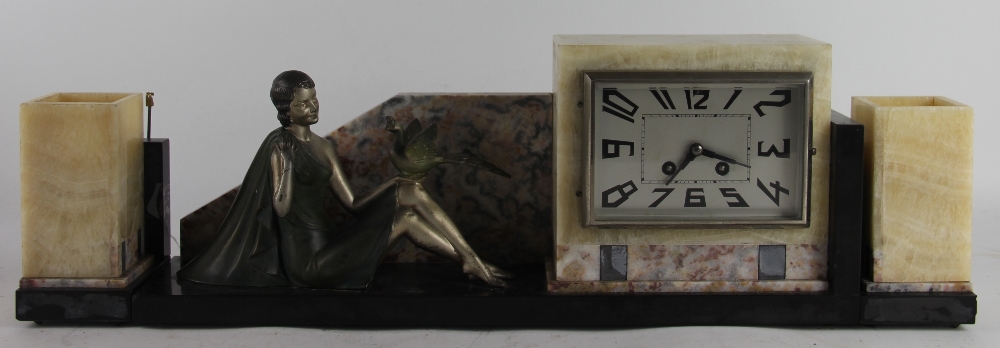 An Art Deco onyx clock garniture, modelled with a painted spelter figure of a female with a bird,