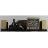 An Art Deco onyx clock garniture, modelled with a painted spelter figure of a female with a bird,