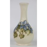 A Moorcroft vase, decorated with blue and white flowers and green foliage, upon a cream ground,
