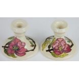 A pair of Moorcroft dwarf candlestick in the Pink Magnolia pattern, against a cream ground,
