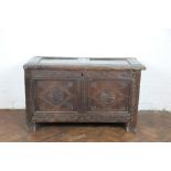 A late 17th century oak coffer, with twin panelled top and front and later carved detailing,