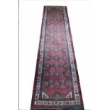 A Caucasian hand woven wool runner, worked with an all over foliate design against a red ground,