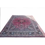 A Persian wool carpet, worked with an overall foliate design against a red ground,