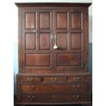 A mid 18th Century oak livery cupboard on chest, with two panelled doors enclosing fixed shelves,