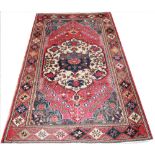 A Persian Hamadan wool rug, worked with a floral gull against a foliate red ground,