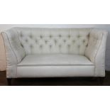 An Edwardian button back salon drop end settee, with foliate ivory upolstery on tapered square legs,