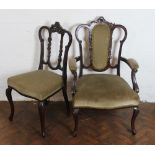 A pair of late Victorian carved mahogany salon chairs, with shaped backs and scroll end arms,