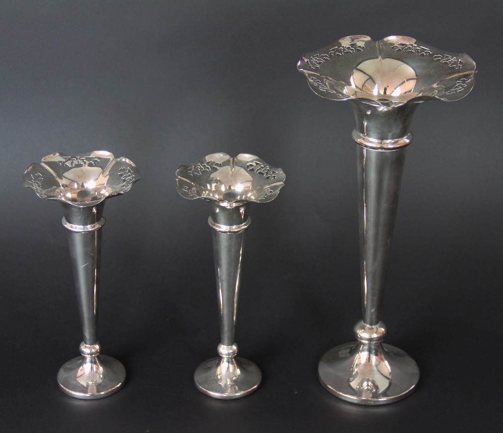 A garniture of three silver plated trumpet vases, each with flared and pierced rim, two 21.