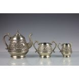 A Burmese white metal tea service, each piece embossed with rural scenes and temples,
