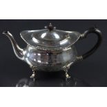 A George V silver teapot, Birmingham 1912, oval form with ebonised finial and handle on shell feet,