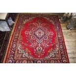 A Tabriz wool ground rug worked with a foliate design against a red ground,