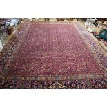 A Persian Tabriz wool carpet worked with a traditional foliate design against a red ground,