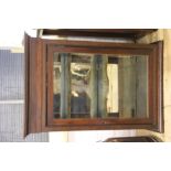 A late Victorian walnut wall cabinet, with bevelled glass door and interior with mirror back,