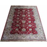 A Kashmir rug worked with an all over foliate design against a red ground,