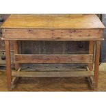 An early 20th century pine school masters desk, with double hinged top, on square legs,