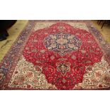 A Persian Caucasian wool carpet worked with an all over foliate design against a red ground, 381cm x