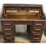 An Edwardian oak roll top desk, with fitted interior and nine drawers, on plinth base,