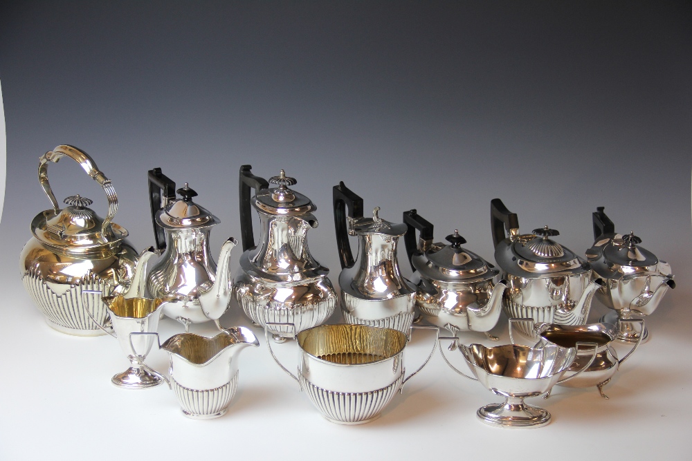 An Edwardian silver plate spirit kettle on stand, a similar decorated three piece tea set,