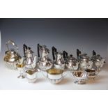 An Edwardian silver plate spirit kettle on stand, a similar decorated three piece tea set,
