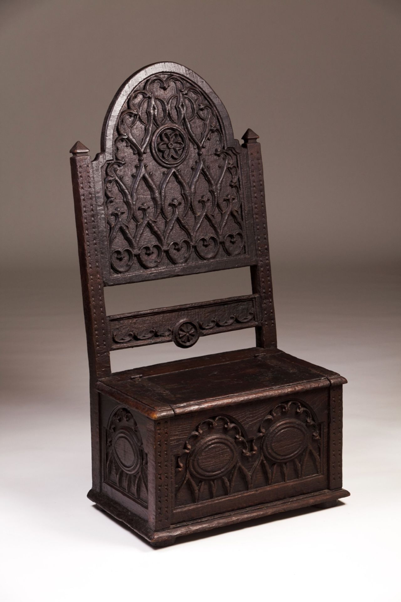 A 16th century oak chair/chest  Tall back with relief Manuelino decoration  Decorated front and