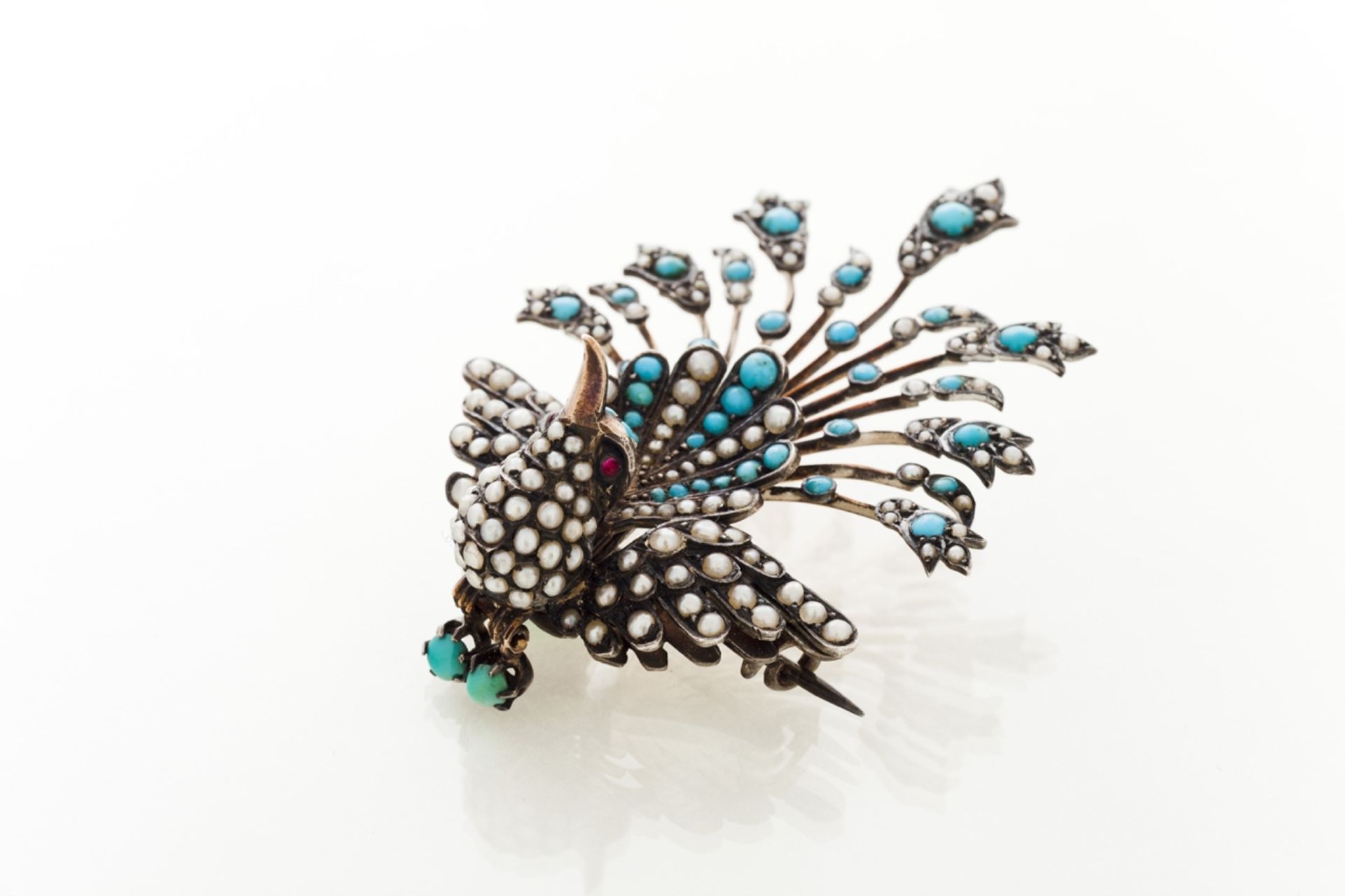 A brooch  Set in silver and gold with half pearls and turquoises  Designed as a bird  19th/20th