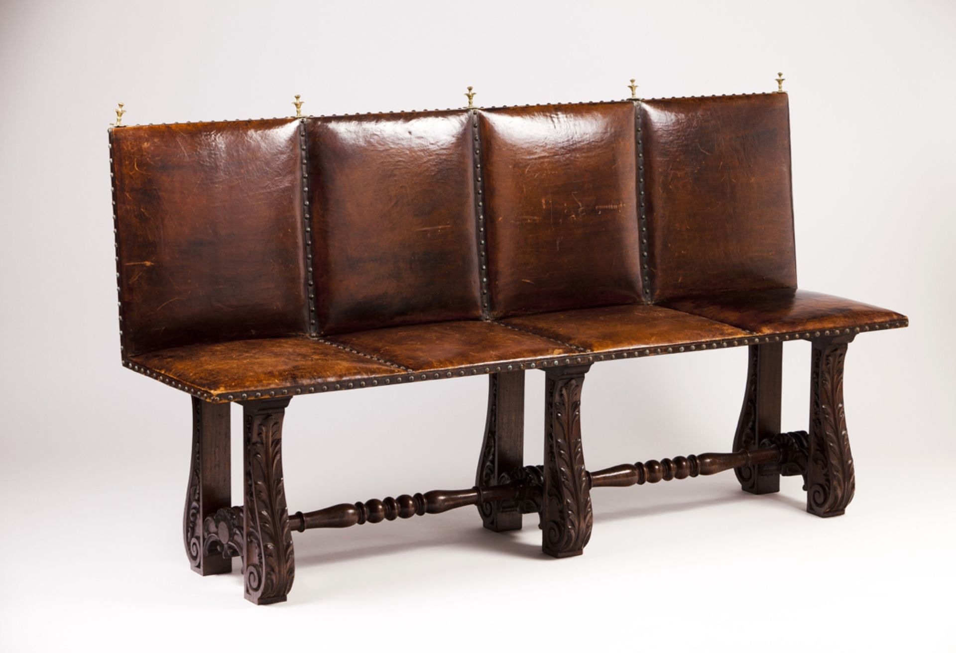 A 19th century Portuguese bench   Leather seat and back  Chestnut feet with carved decoration